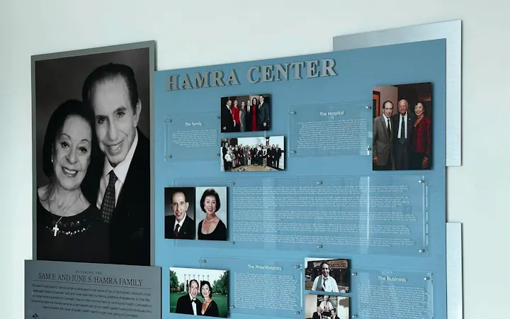 Blue display board titled HAMRA CENTER with a large black-and-white portrait on the left and several photo panels.
