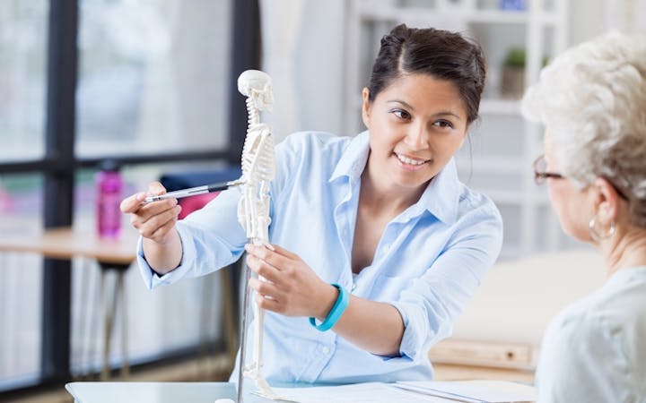 An individual helps explain bone health to a woman.