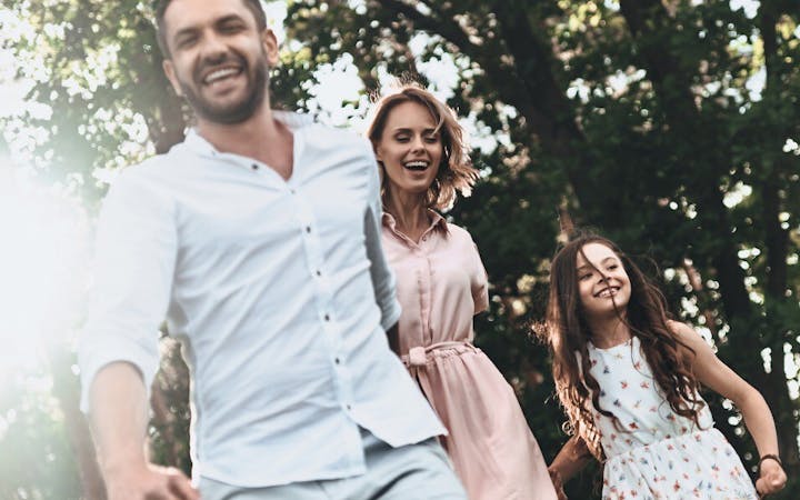 A family laughs together in the sunlight.
