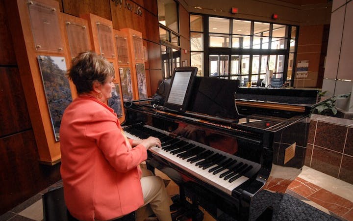 Volunteer playing the piano in the lobby of Cox Health