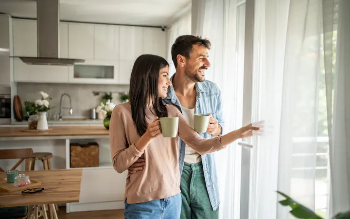Couple looking out a window at clearing skies after a storm