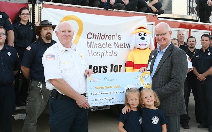 Marshfield Fire Department officers present a check to CMH Hospitals at CoxHealth