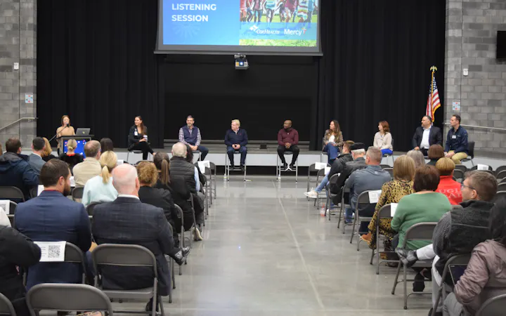 Panelists on stage with screen reading 'Children's Services Listening Session'.