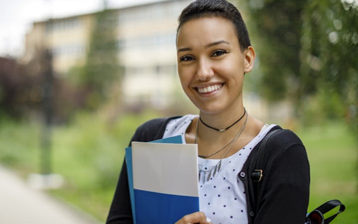 A woman stands with a folder.