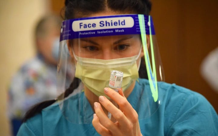 A health care worker prepares to give a COVID-19 vaccine.