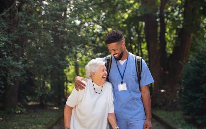 a nurse and elder woman walking on sidewalk
