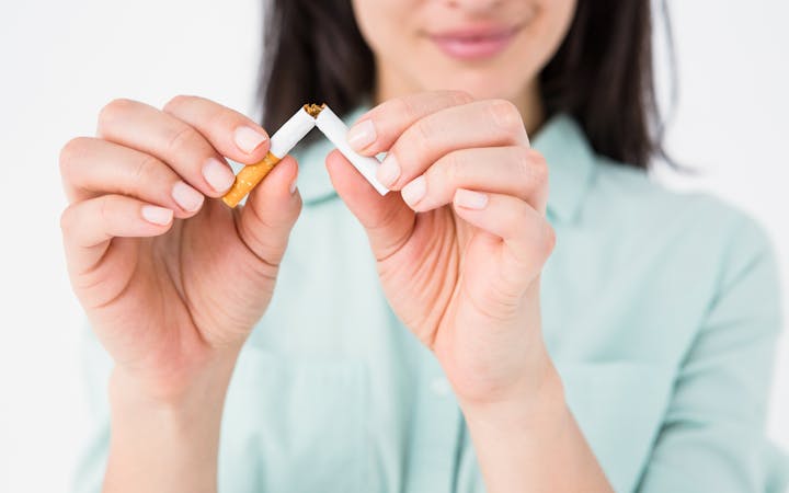 A woman breaks a cigarette in half.