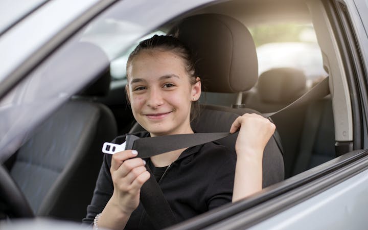 A young adult sits in a car.