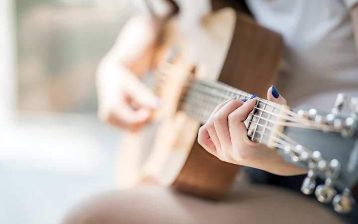 A woman plays the guitar.