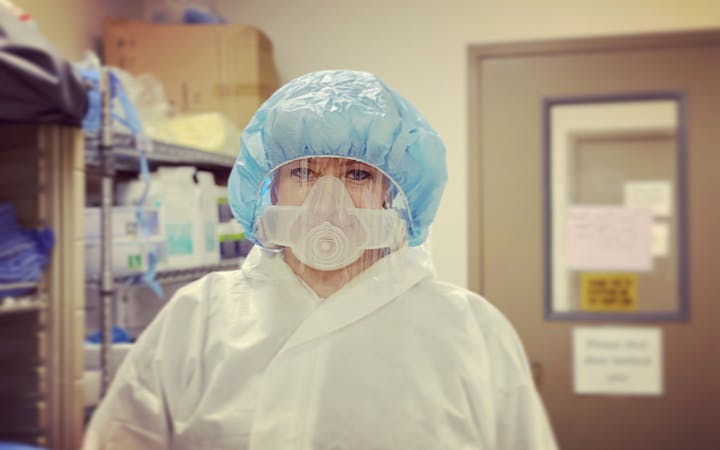 A nurse stands in PPE.