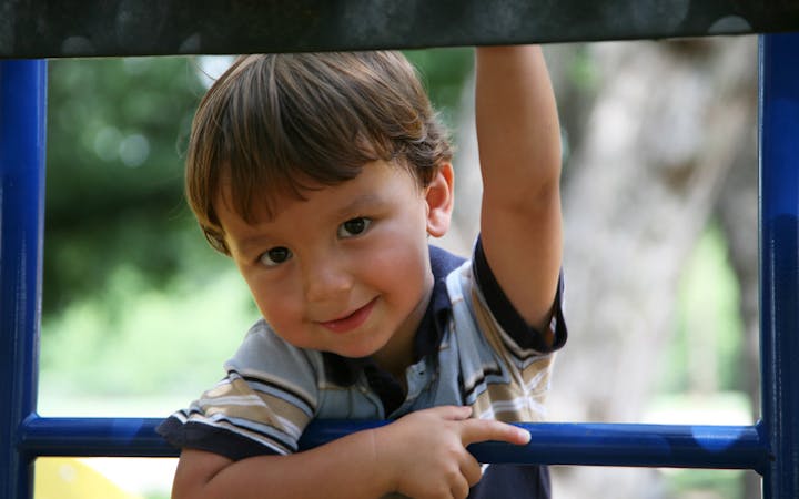 a child playing on a playground smiles into the camera