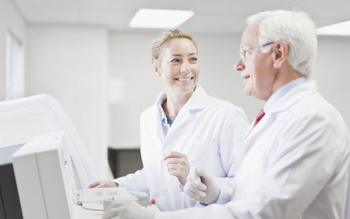 Two people talk while looking at a computer.