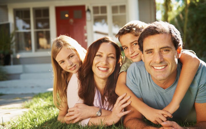 A family sits in front of a house.