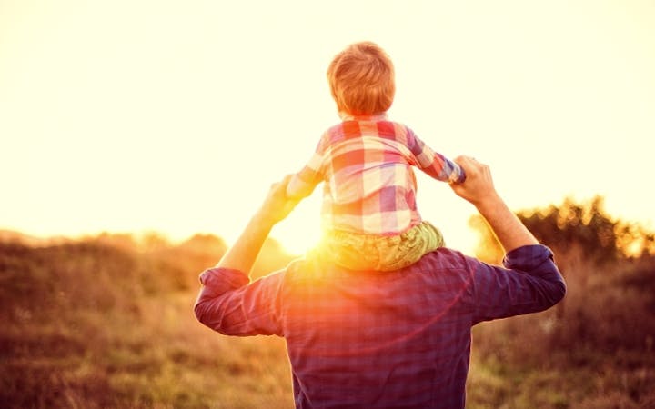 A man holds a child on his shoulders.