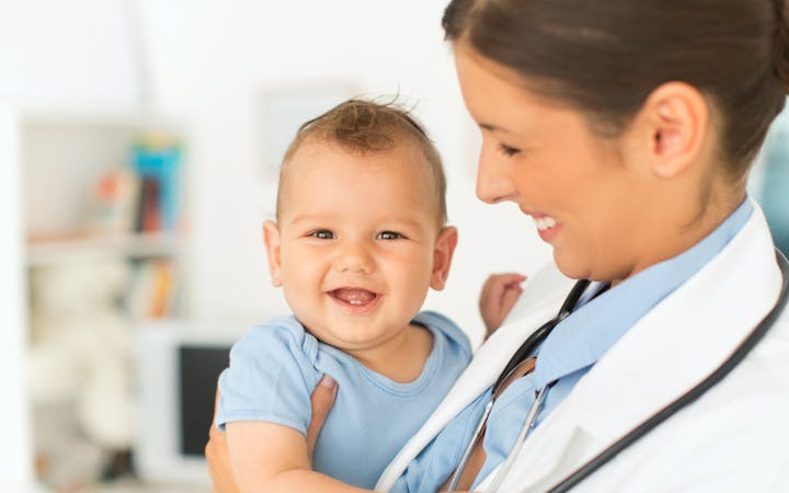 A provider holds a smiling baby.