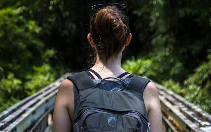 A female hiker with a backpack walking outside.
