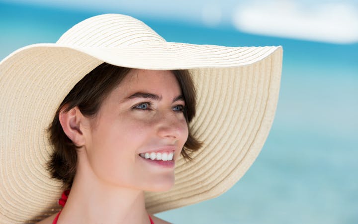 Woman on the beach wearing a floppy hat.